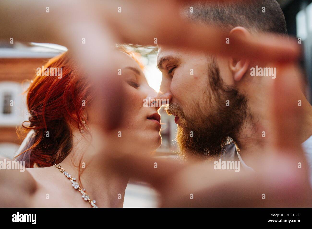 Newly wed couple kissing. Shot through a frame, made with their hands Stock Photo