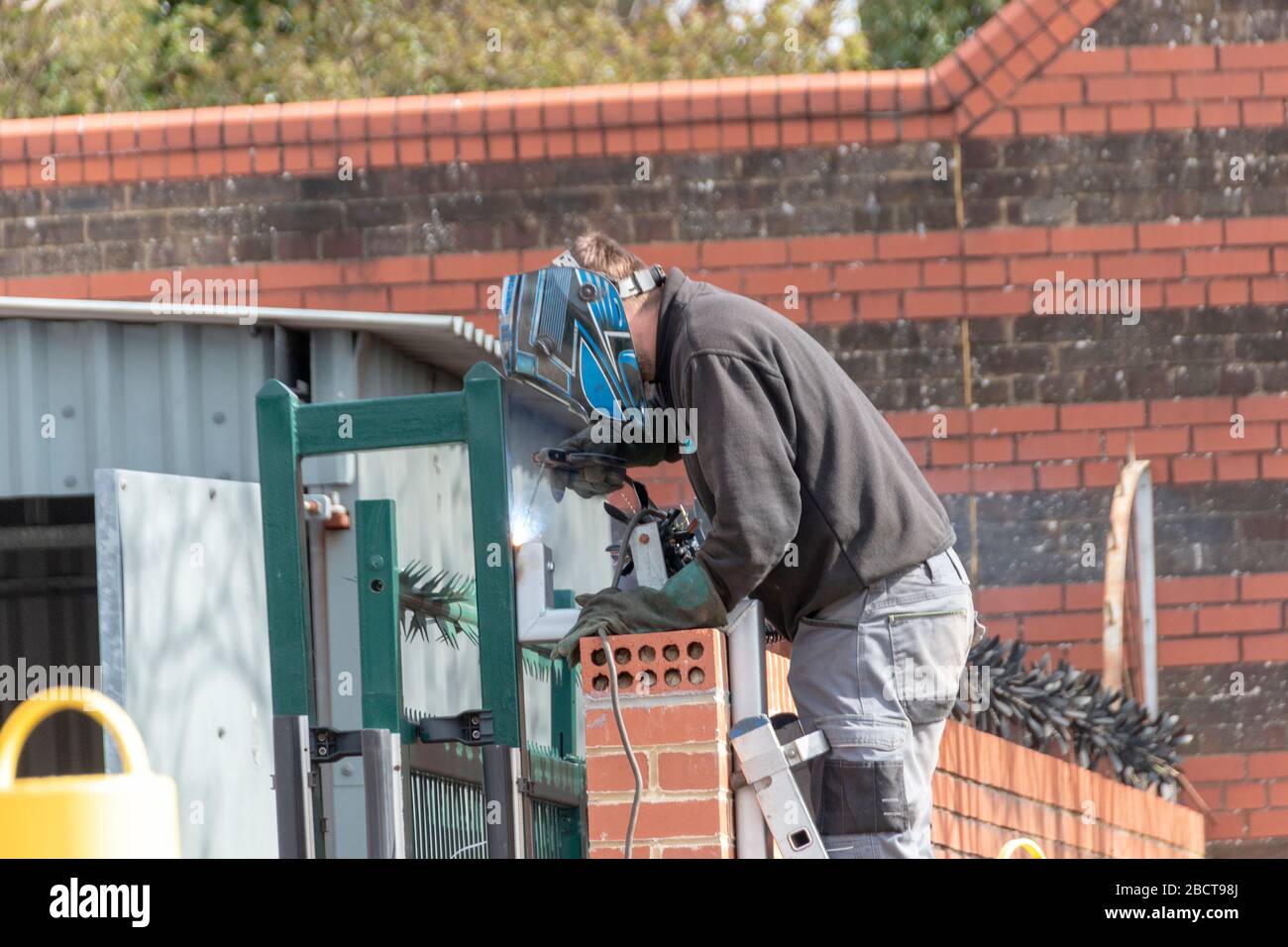 Bristol-April-2020-England, a close up view of a man welding a metal pipe to the main security gate Stock Photo