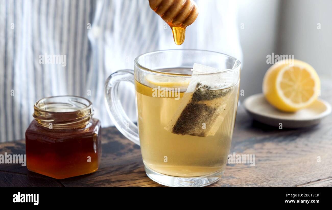 Green Tea With Honey. Person adding natural honey to cup of green tea