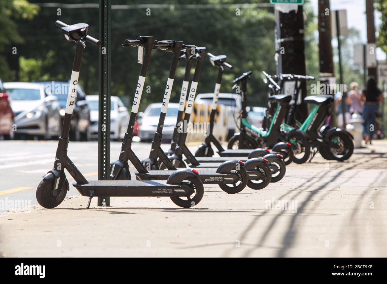 Several motorized scooters for rent sit lined up and parked on a sidewalk  at Piedmont Park on August 10, 2019 in Atlanta, GA. Stock Photo
