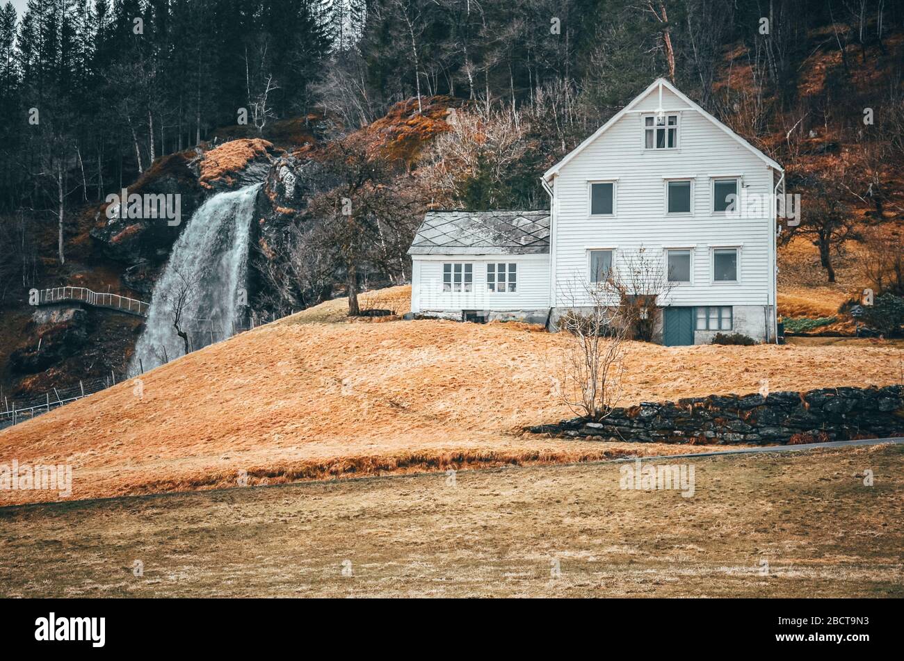 Red house in Norway near by big waterfall. Original wallpaper from very beginning of spring Stock Photo