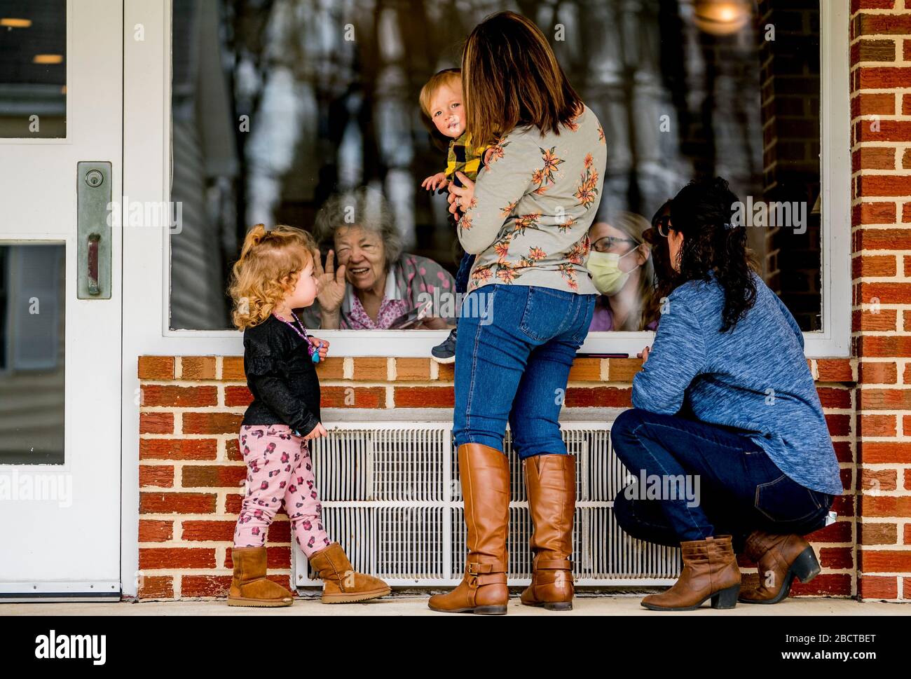 North East, MD, USA. 5th Apr, 2020. April 5, 2020: Grandmother Karen Bowman, her daughter Tiffany Sadler and great-grand children Audrey, 3, and Chase Sadler, 1, visit with Della Simpson, as nurse Shannon Green helps, at Calvert Manor Nursing Home and Rehabilitation Center on Palm Sunday in North East, Maryland on April 5, 2020. Scott Serio/ESW/CSM/Alamy Live News Stock Photo