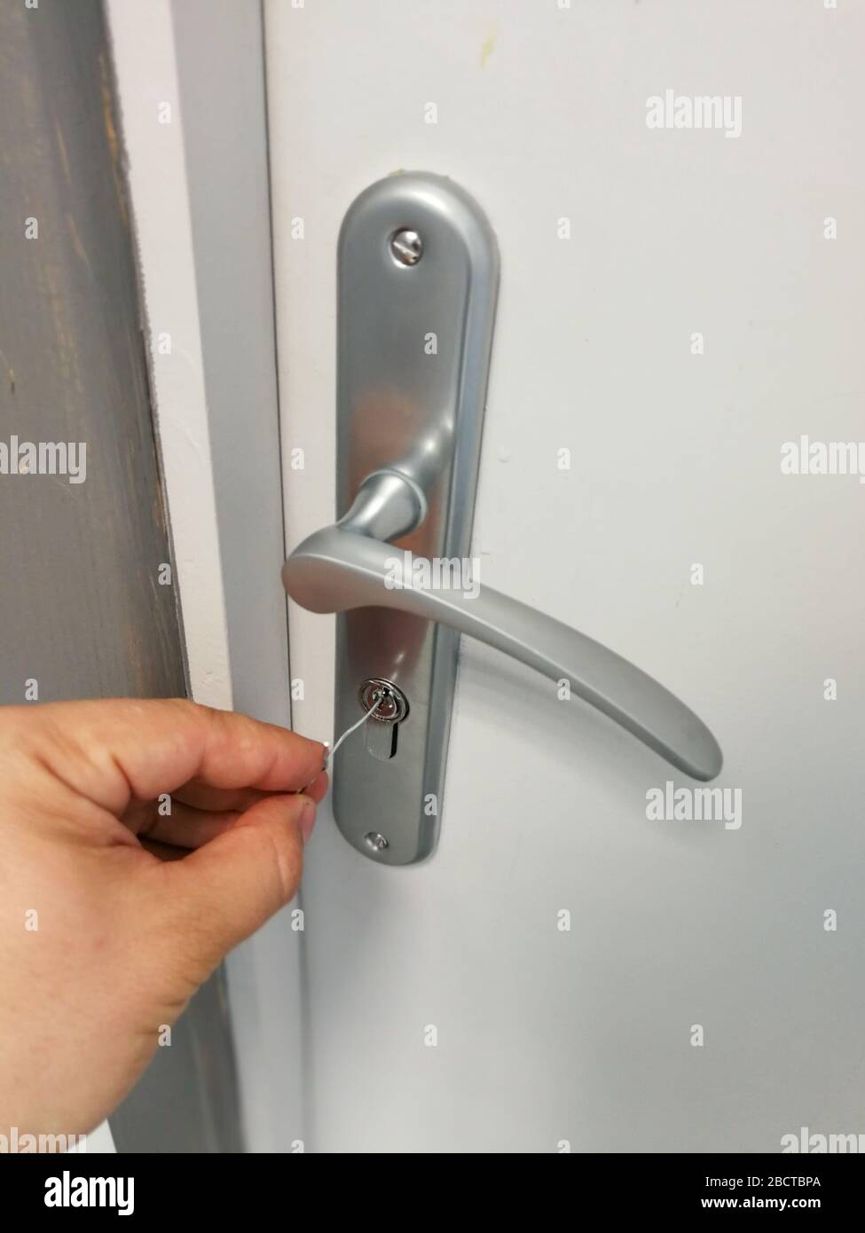 Small metal wire inserted in the keyhole of the door for unlocking doors without key Stock Photo