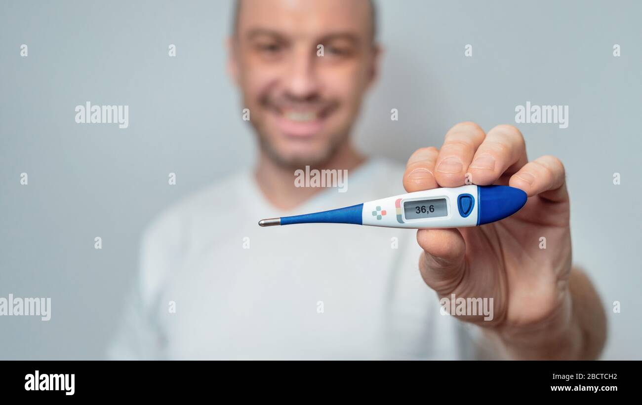 Healthy Man Showing Thermometer With Normal Temperature Over Gray