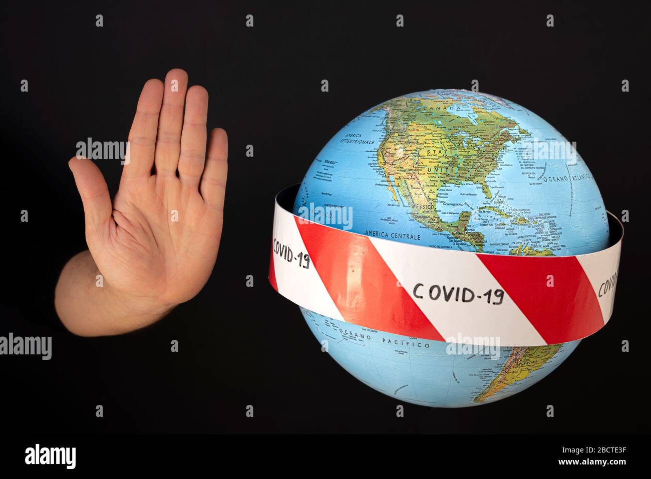 Stop the coronavirus. Hand imposes stop to spread of coronavirus, COVID-19. Planet earth with caution barrier tapes. In the foreground the United Stat Stock Photo
