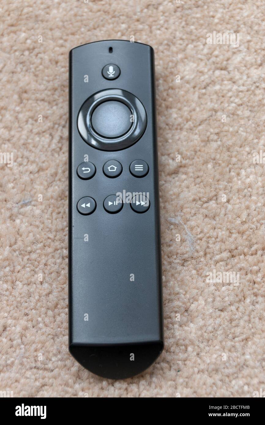 a close up view of a black smart tv remote placed on the carpet Stock Photo