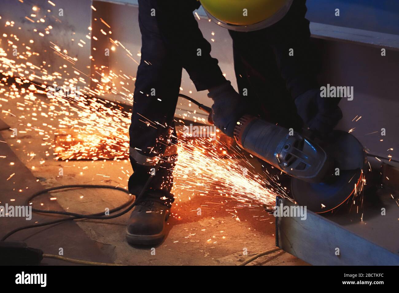 Professional worker cuts metal by angle grinder machine. Fountain of sparks. Fire safety at