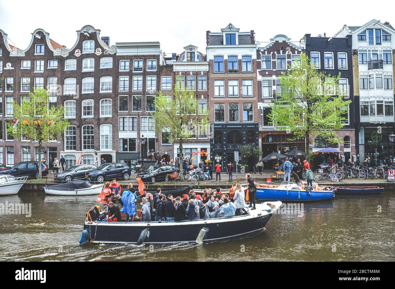 Amsterdam, Netherlands - April 27, 2019: People on party boats celebrating the Kings day, Koningsdag, the birthday of the Dutch King Willem-Alexander. Overcrowded boats on the canal. Stock Photo