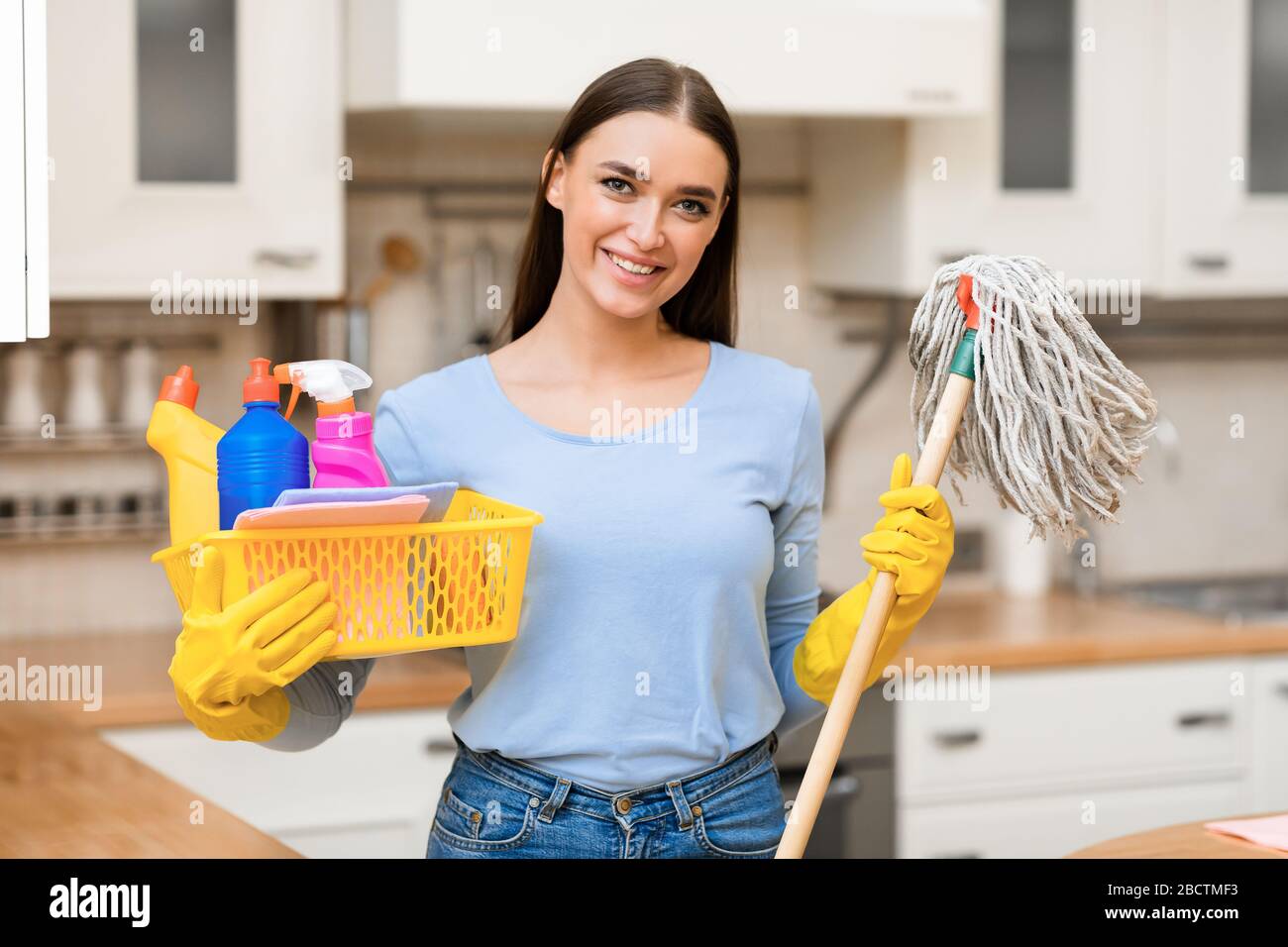 Young woman holding mop and plastic bucket with detergents Stock Photo