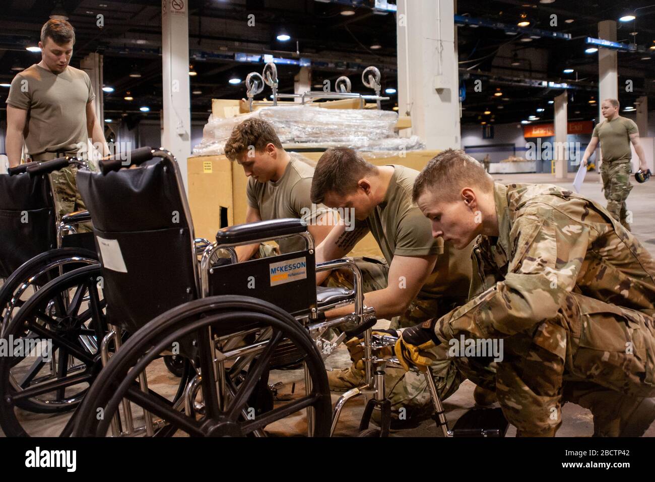 Members of the Illinois Air National Guard assemble medical equipment at the McCormick Place Convention Center in response to the COVID-19 pandemic in Chicago, Ill., March 30, 2020. Approximately 30 members of the Illinois Air National Guard were activated to support the US Army Corps of Engineers and the Federal Emergency Management Agency (FEMA) to temporarily convert part of the McCormick Place Convention Center into an Alternate Care Facility (ACF) for COVID-19 patients with mild symptoms who do not require intensive care in the Chicago area. (U.S. Air Force Photo by Senior Airman Jay Grab Stock Photo