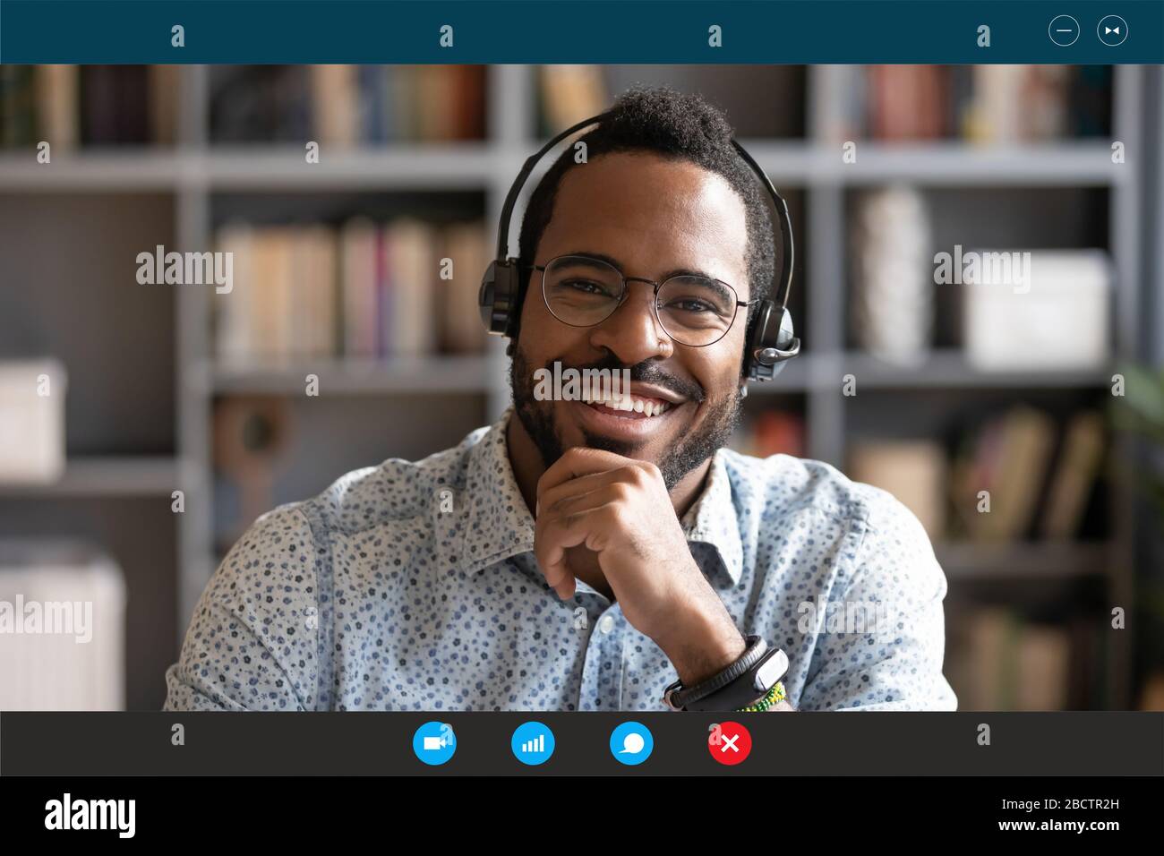African man wear headset sit at desk looking at camera Stock Photo