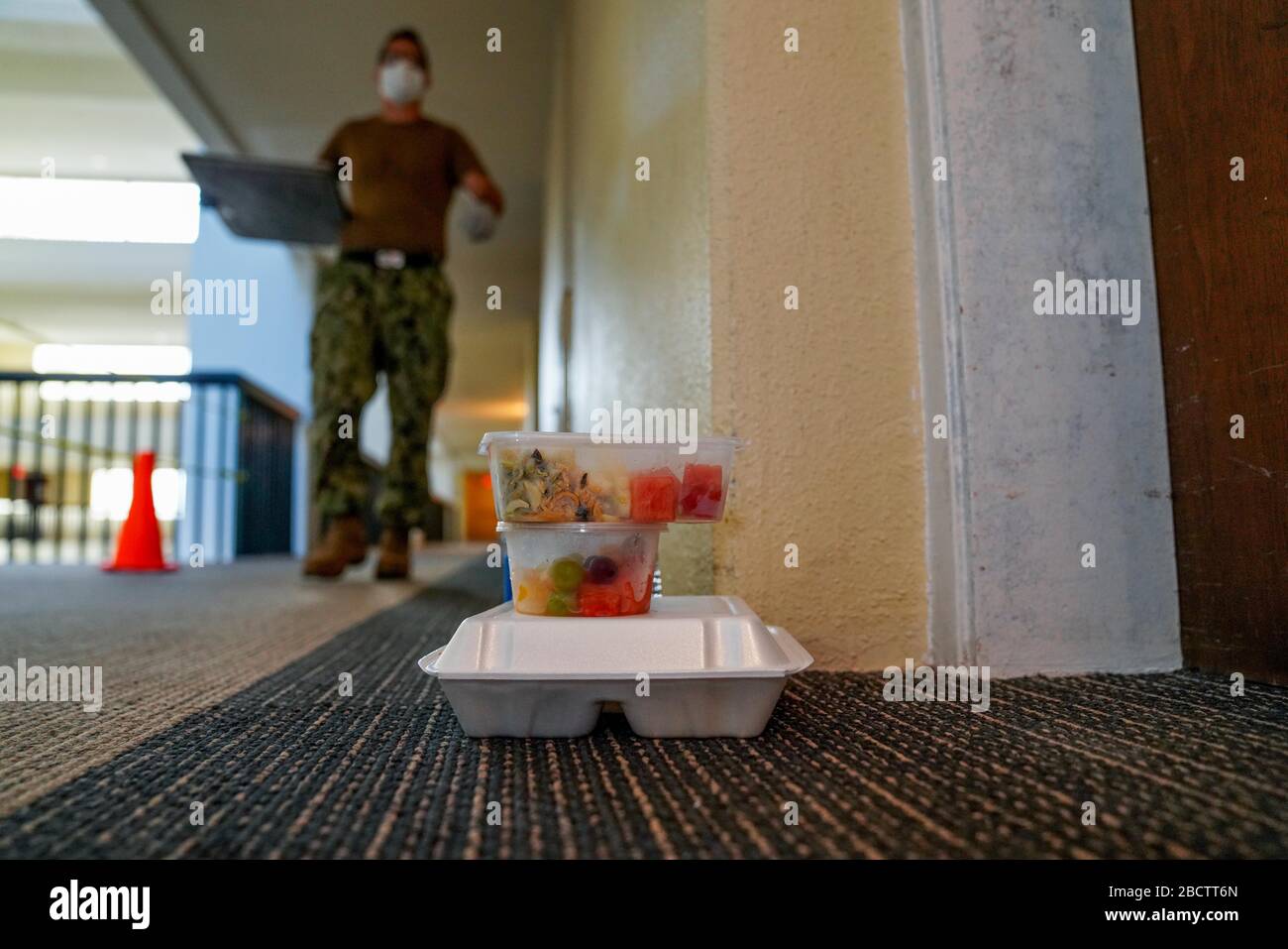 A U.S. Navy sailor delivers food to hotel rooms where sailors from the aircraft carrier USS Theodore Roosevelt who have tested negative for COVID-19 are quarantined April 3, 2020 in Tamuning, Guam. The sailors will be required to remain in quarantine for at least 14 days. Previously the ships commanding officer Capt. Brett Crozier was relieved of duty March 31, 2020 after pleading for help to stem the spread of COVID-19 cases on his ship. Stock Photo