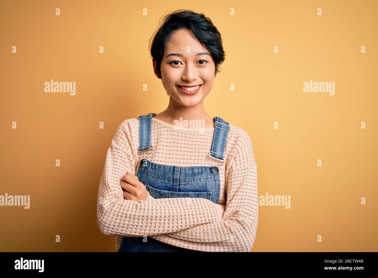 Young beautiful asian girl wearing casual denim overalls over isolated ...