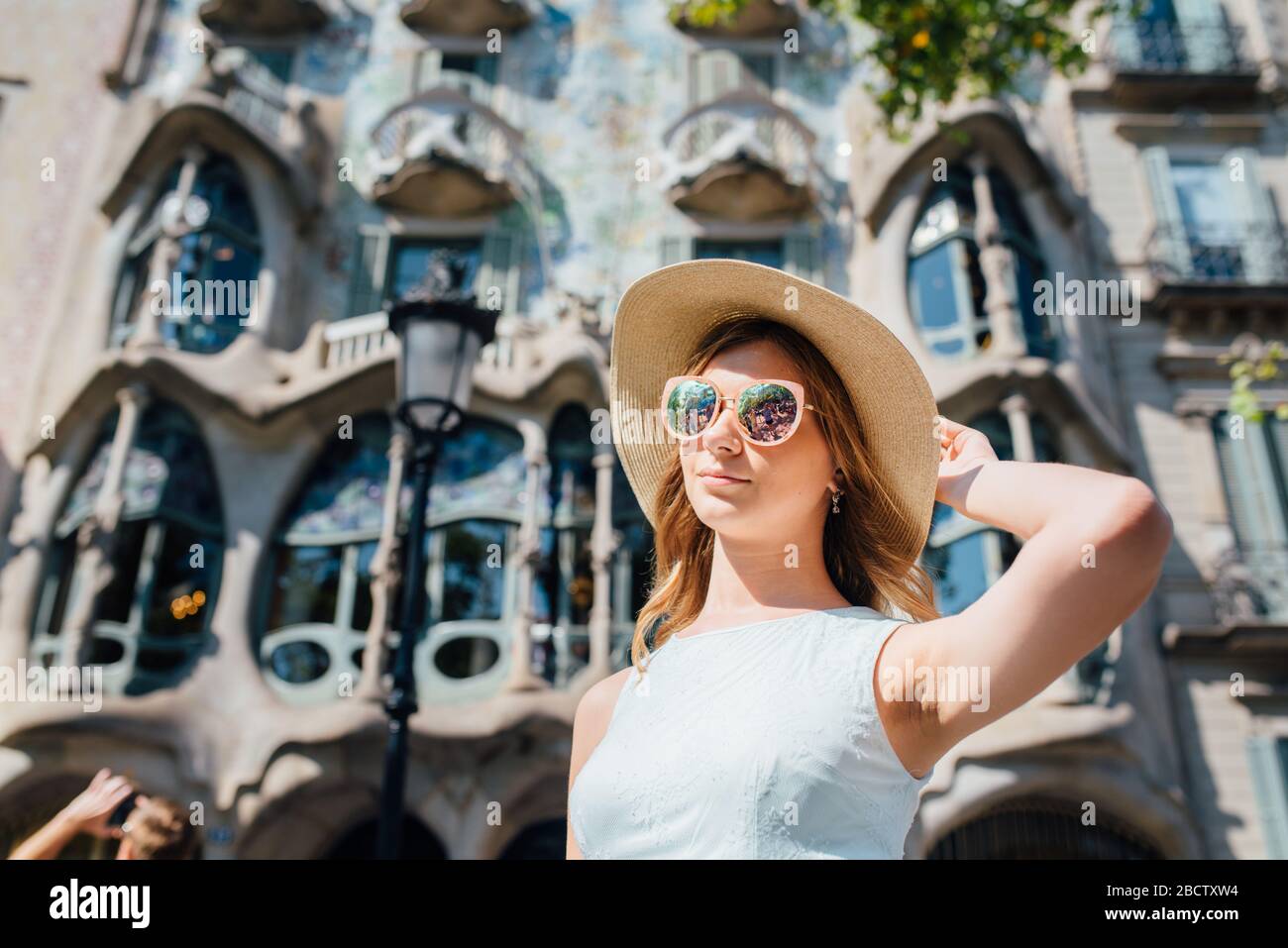 Portrait of a female tourist from the Casa Batllo by Antonio Gaudi in the background on a summer day Stock Photo