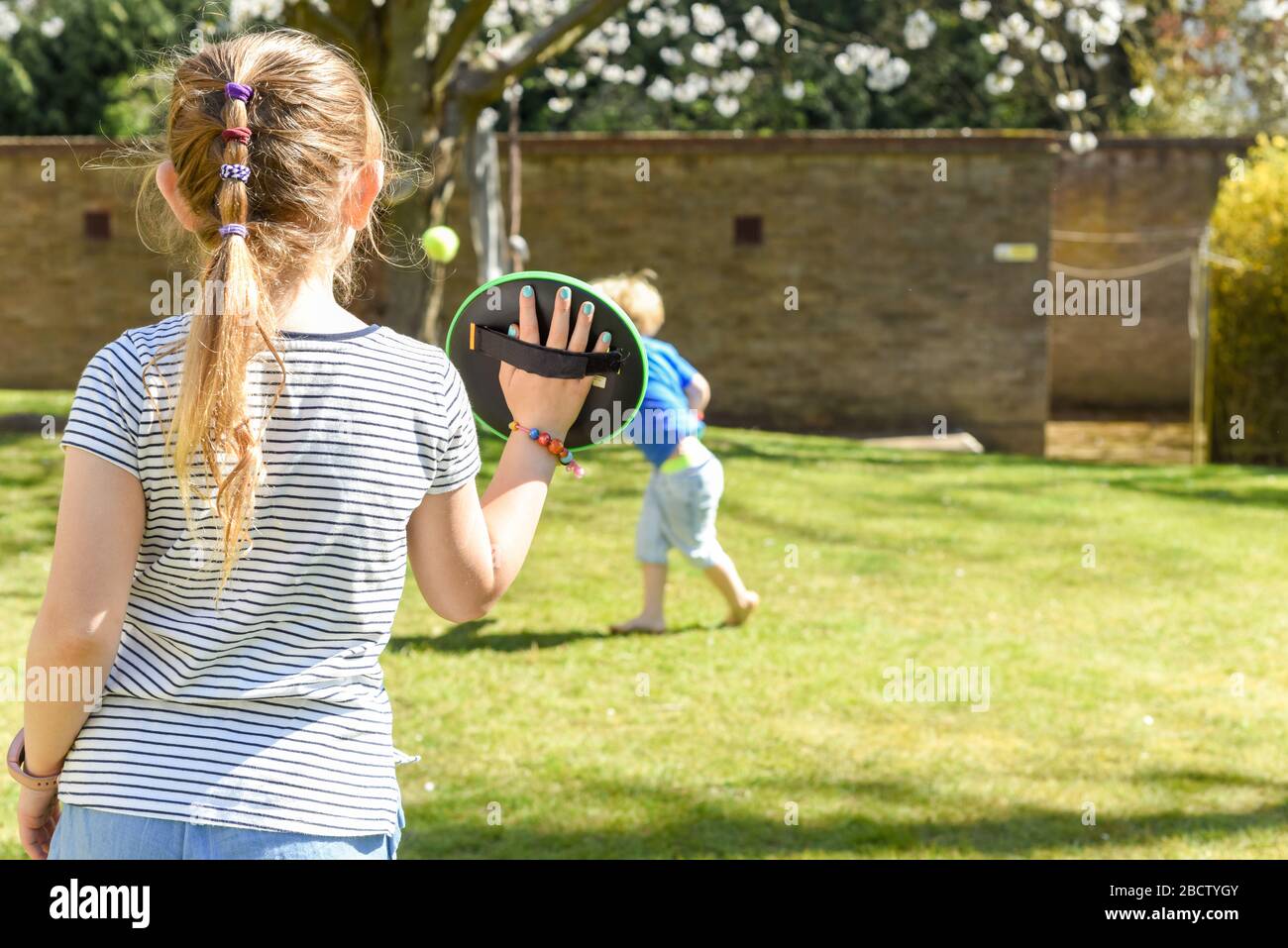 Children playing outside a brother and sister play a ball game in a garden Stock Photo Alamy