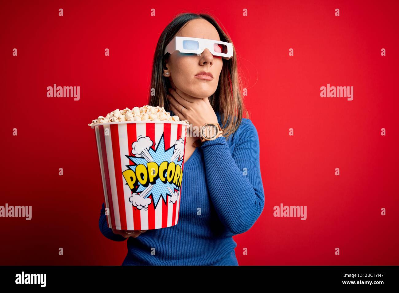 Young blonde woman wearing 3d glasses and eating pack of popcorn