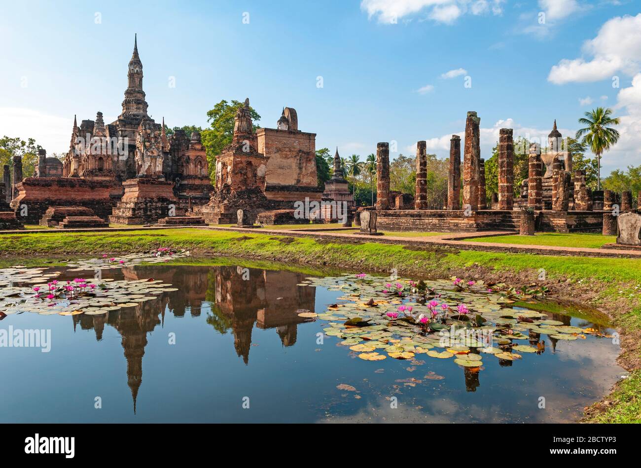 The Wat Mahathat temple reflecting in a pond with lotus flowers, Sukhothai, Thailand. Stock Photo