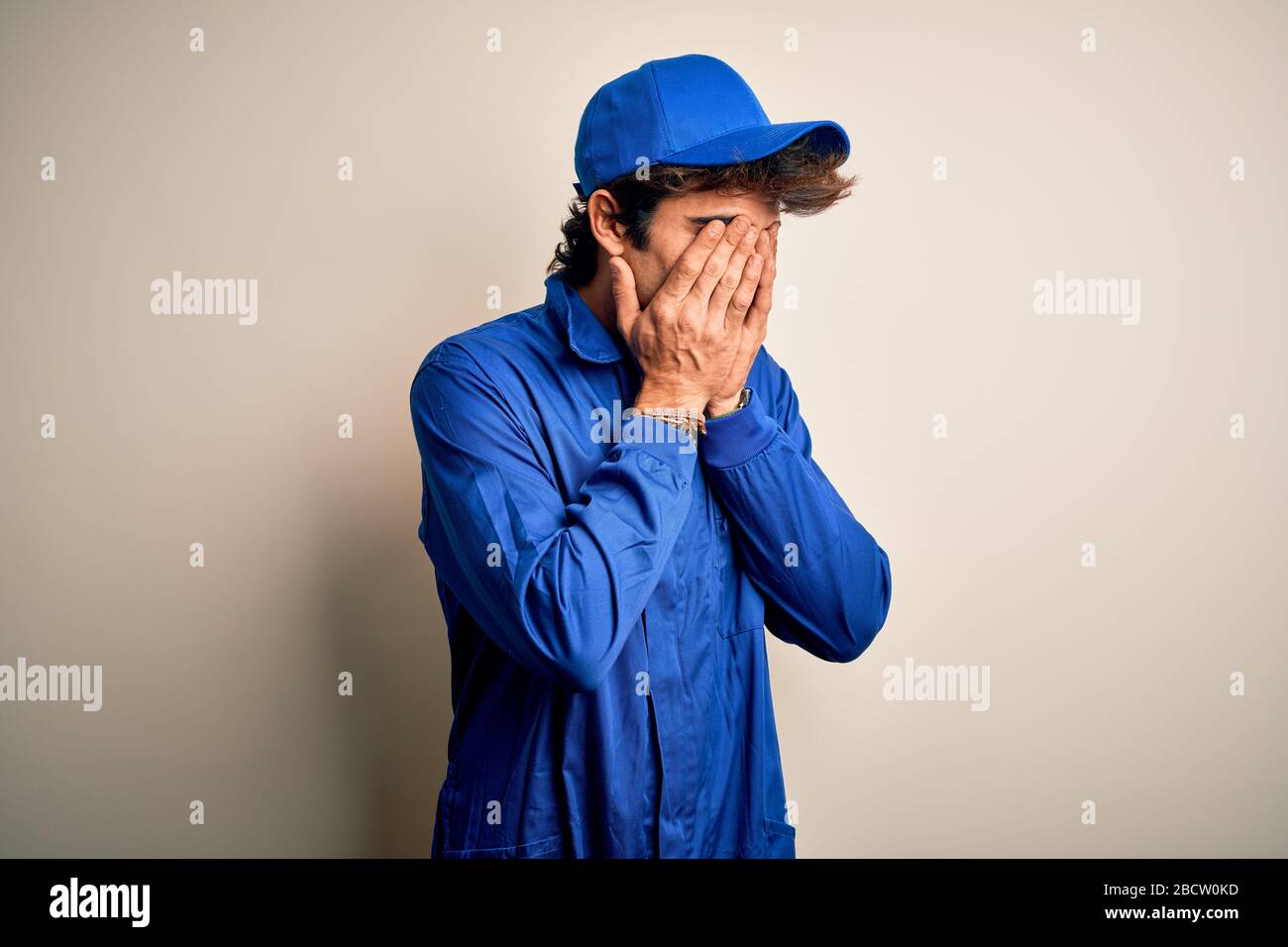 Young mechanic man wearing blue cap and uniform standing over isolated ...