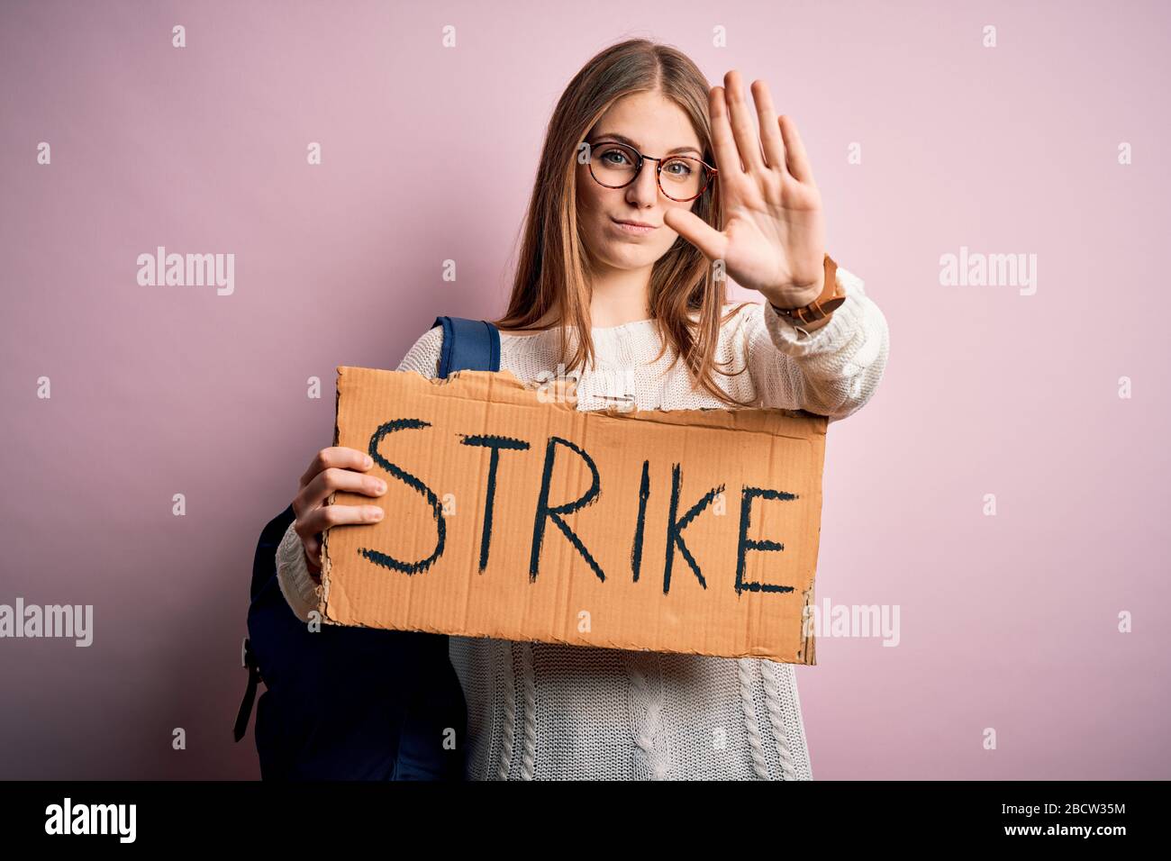 Young beautiful redhead activist woman holding banner with strike ...