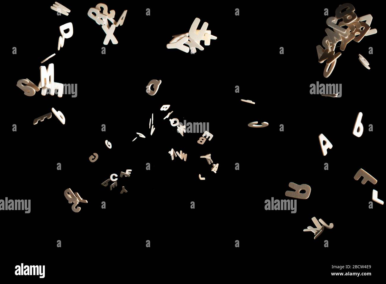 Real Wood Letters Flying away Isolated on Black Background Stock Photo