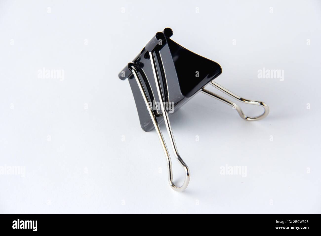 Large black paper clip for papers on white background. Stacking papers