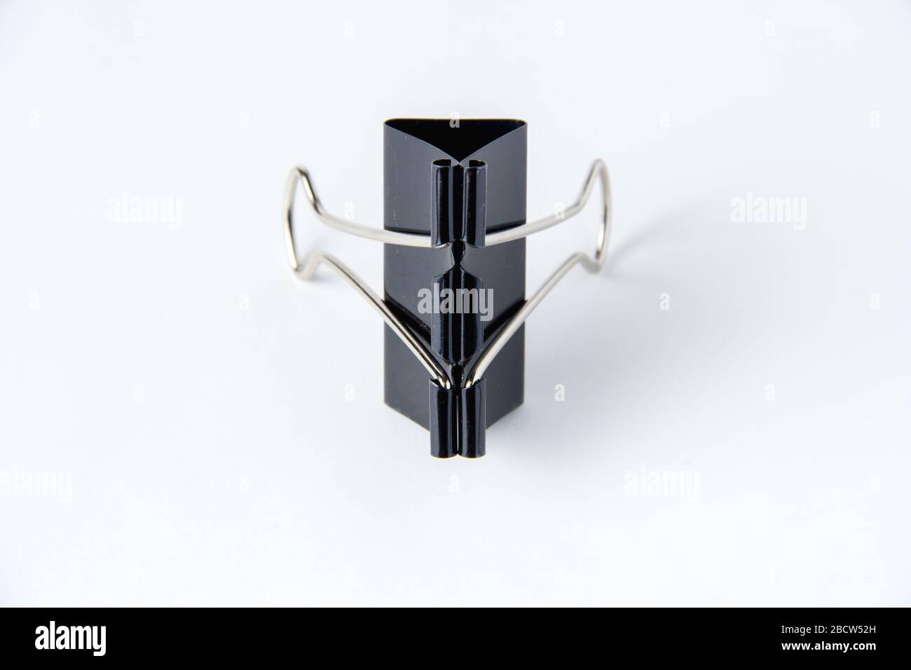Large black paper clip for papers on white background. Stacking papers