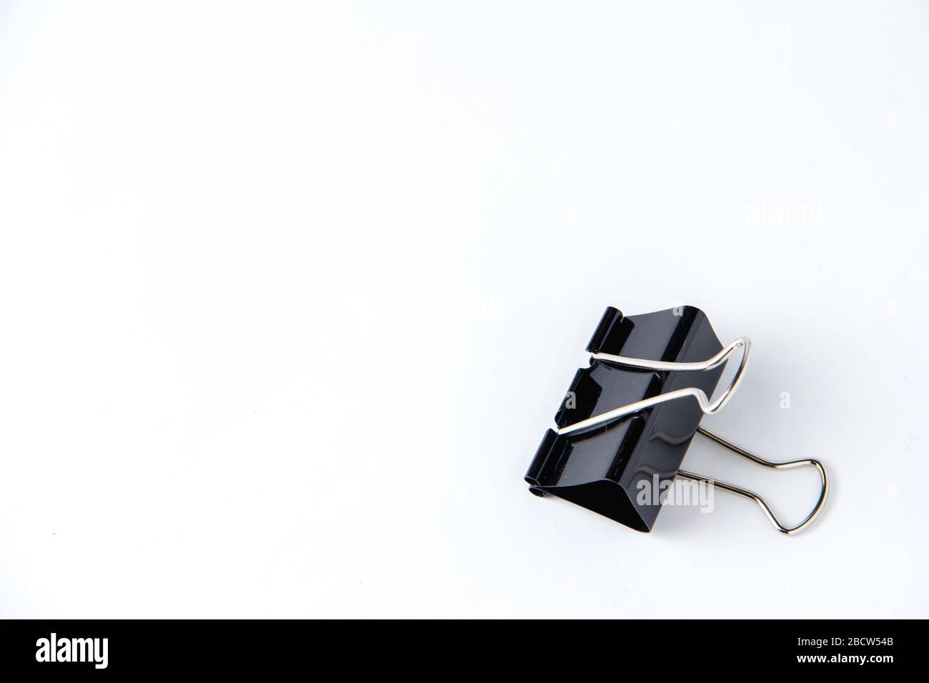 Large black paper clip for papers on white background. Stacking papers