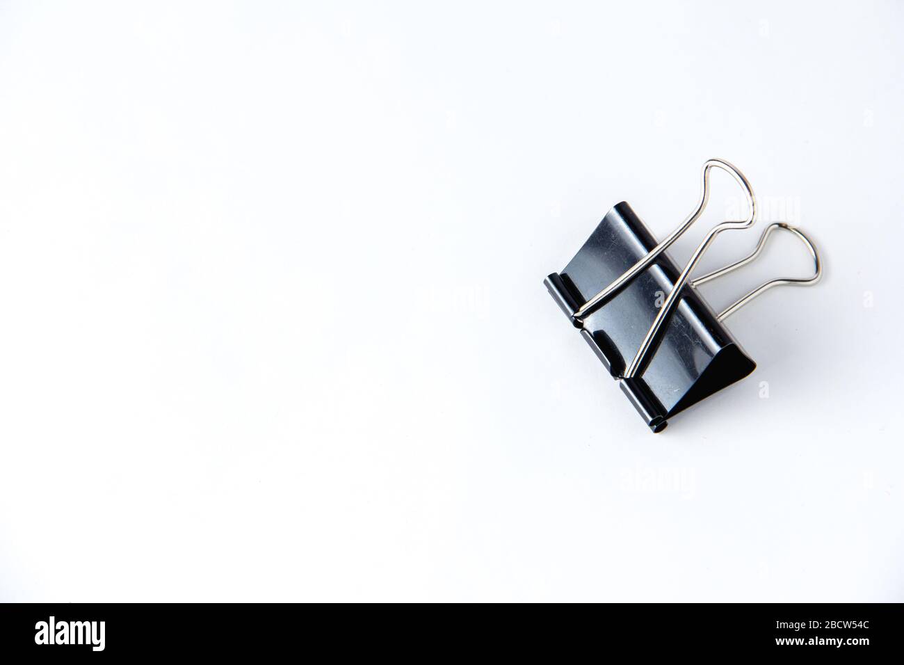 Large black paper clip for papers on white background. Stacking papers Stock Photo