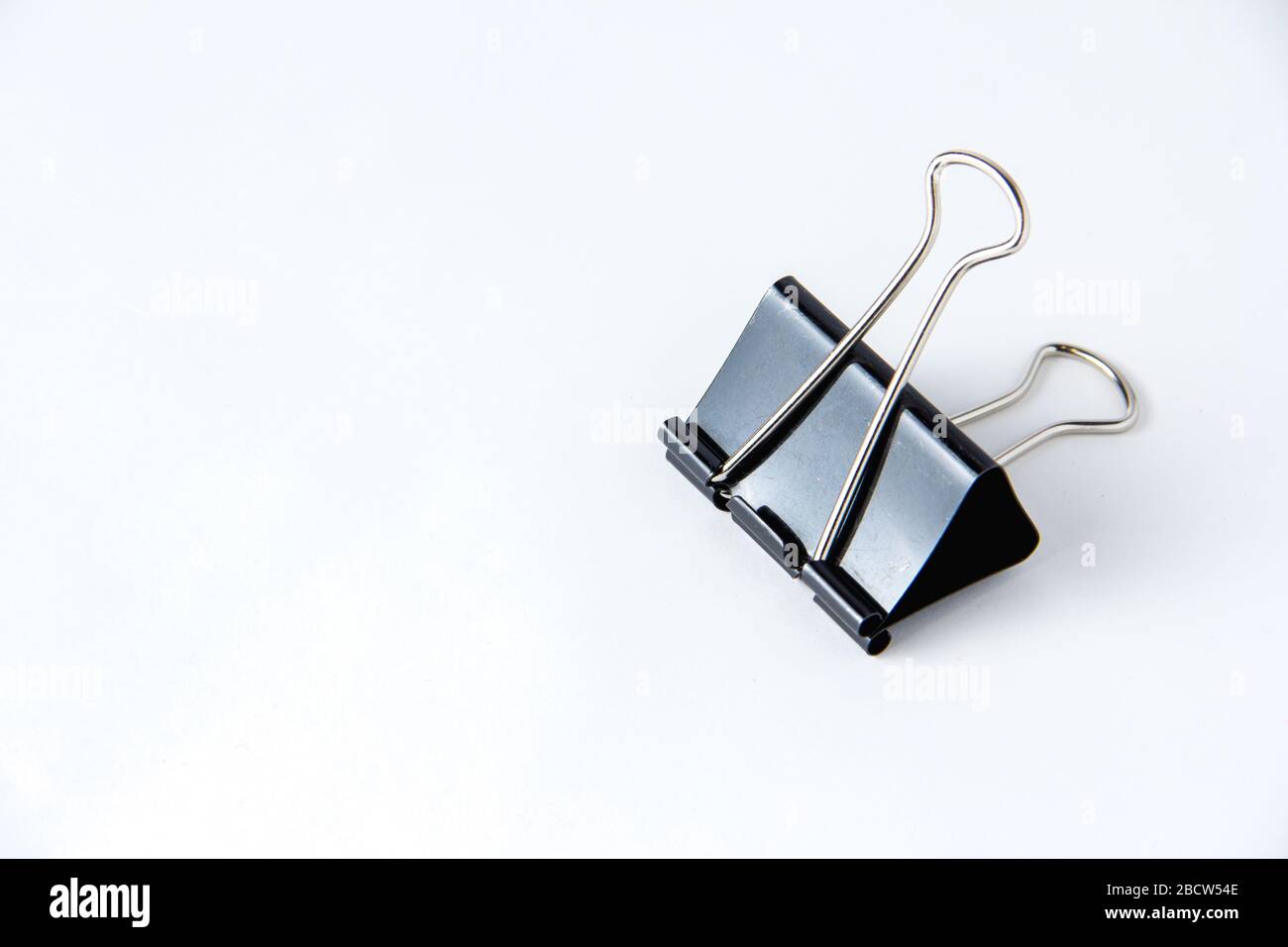 Large black paper clip for papers on white background. Stacking papers