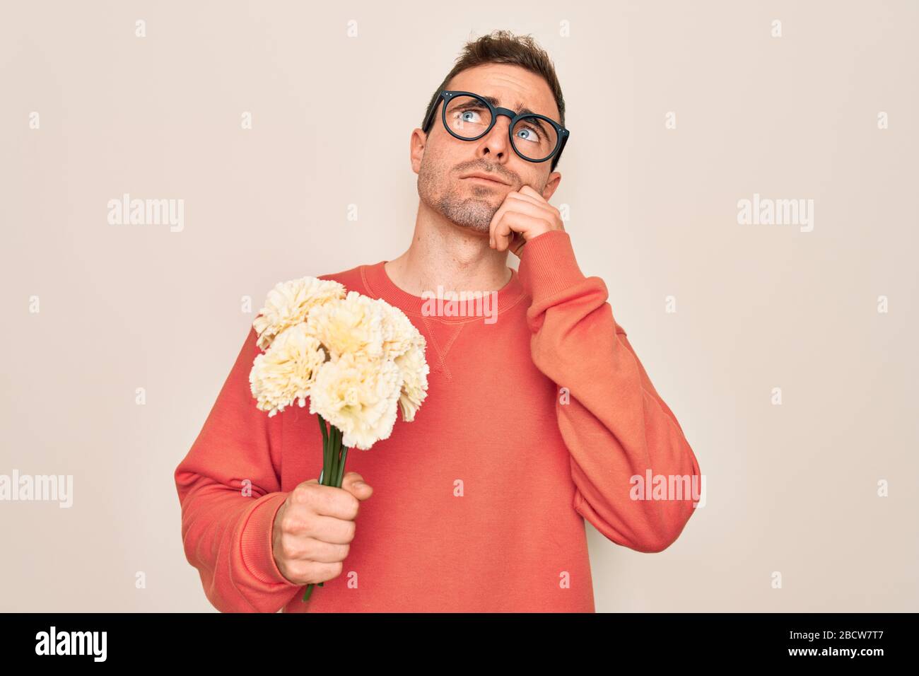 Young handsome man with blue eyes holding bouquet of flowers over white ...