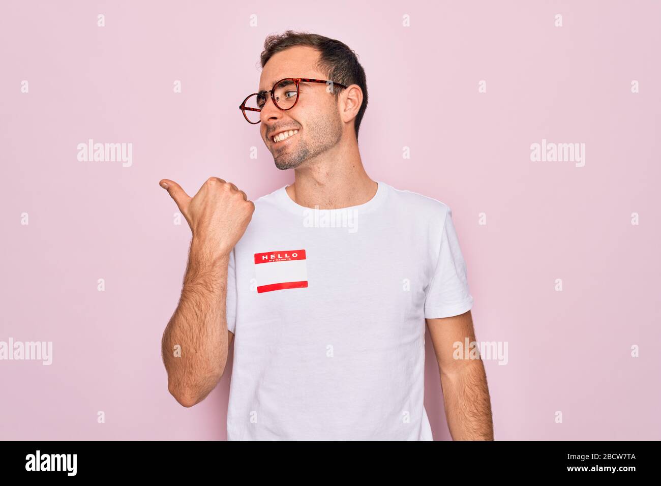 Handsome man with blue eyes wearing sticker with hello my name is ...