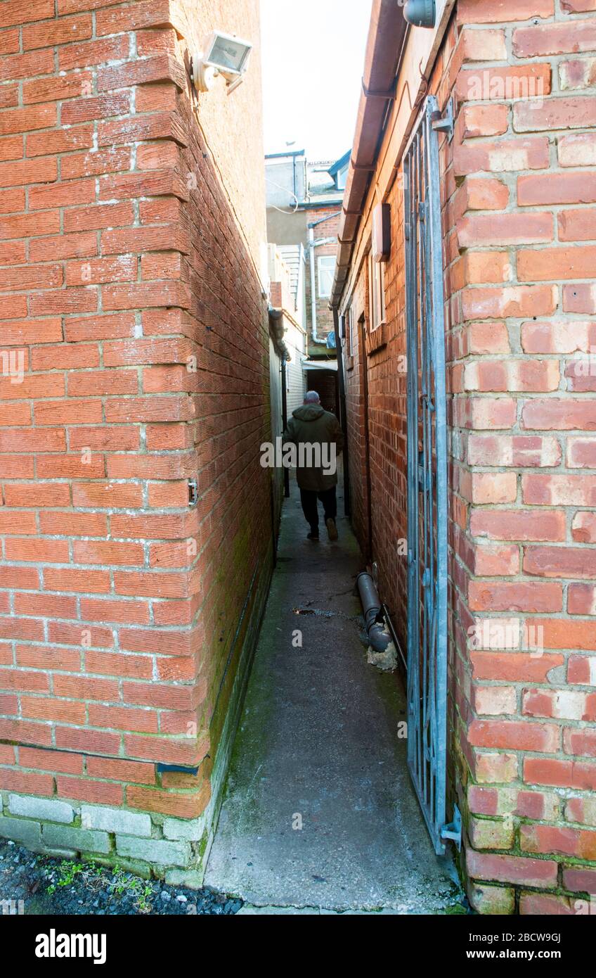 Person walking along a narrow alleyway between shops leading from Market Square to car park at Poulton le Fylde Lancashire England United Kingdom. Stock Photo