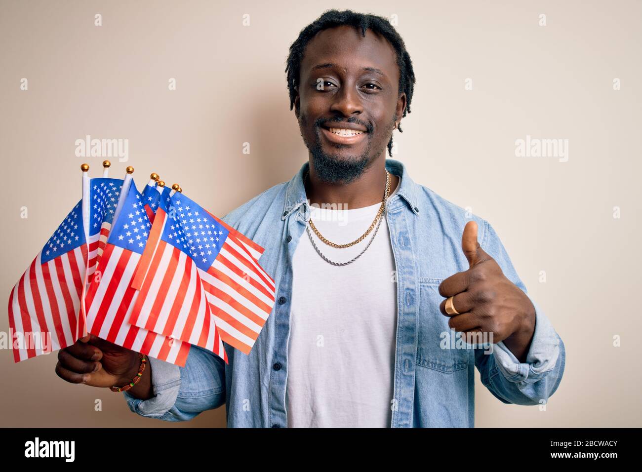 Young african american patriotic man holding united states flags over ...