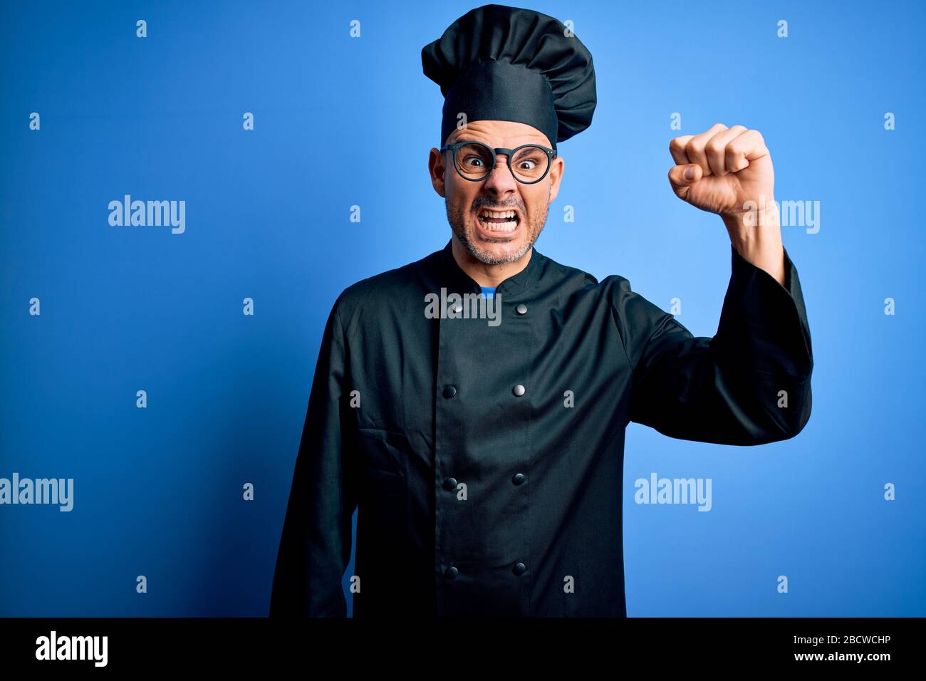 Young handsome chef man wearing cooker uniform and hat over isolated ...