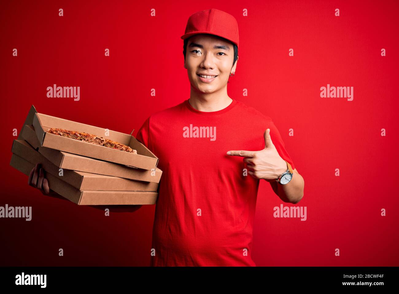 Young handsome chinese delivery man holding deliver boxes with Italian
