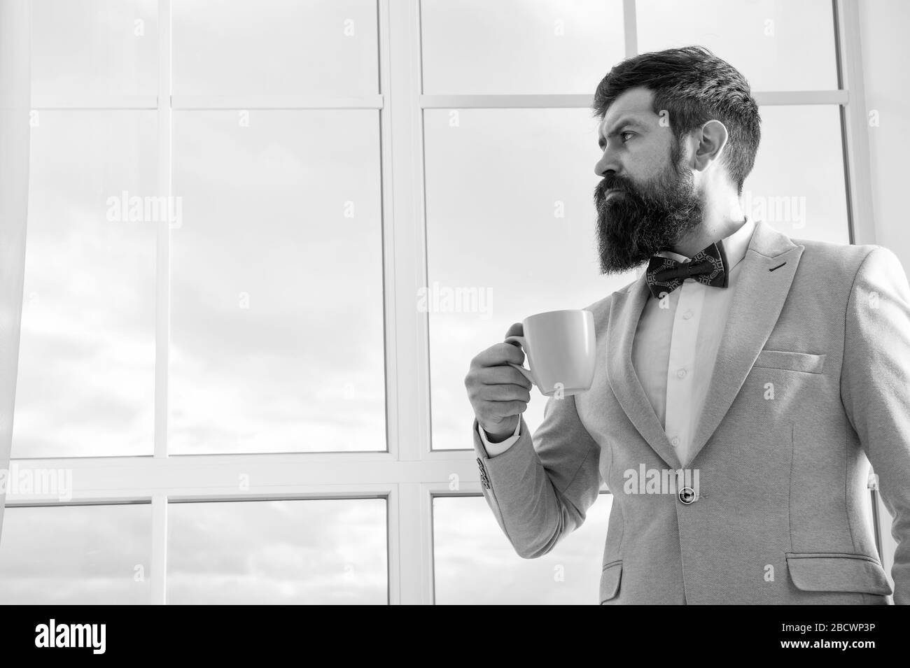 modern businessman. thoughtful bearded man drink coffee. businessman in modern formal outfit. modern life. business man at window. future success. morning inspiration. copy space. modern office. Stock Photo
