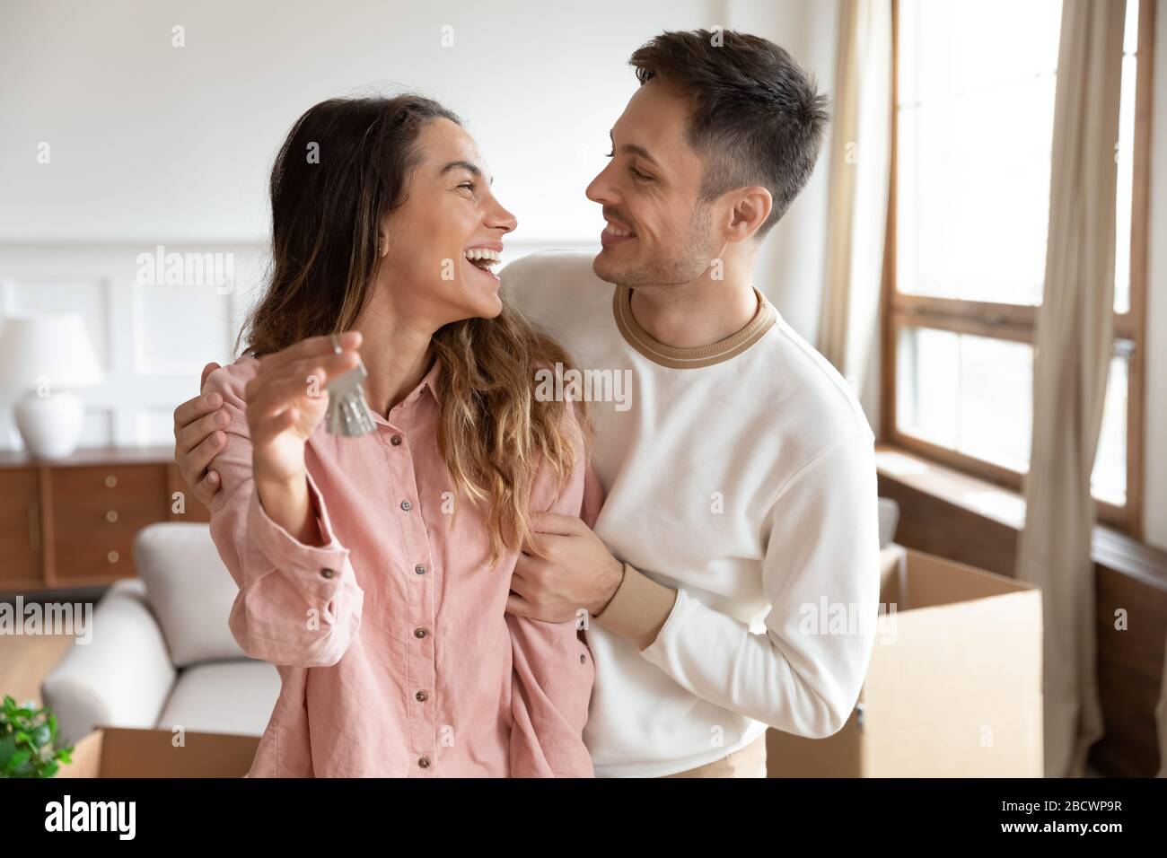 Happy homeowners cuddling, amazed by real estate purchase. Stock Photo
