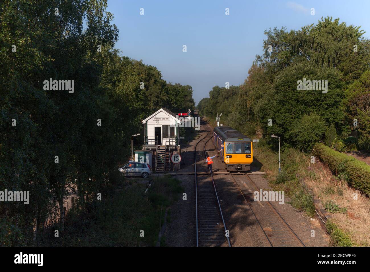 Northern Rail / Northern Trains class 142 pacer142029 at Rainford   junction signalbox with the signal man signal man collecting the single line token Stock Photo