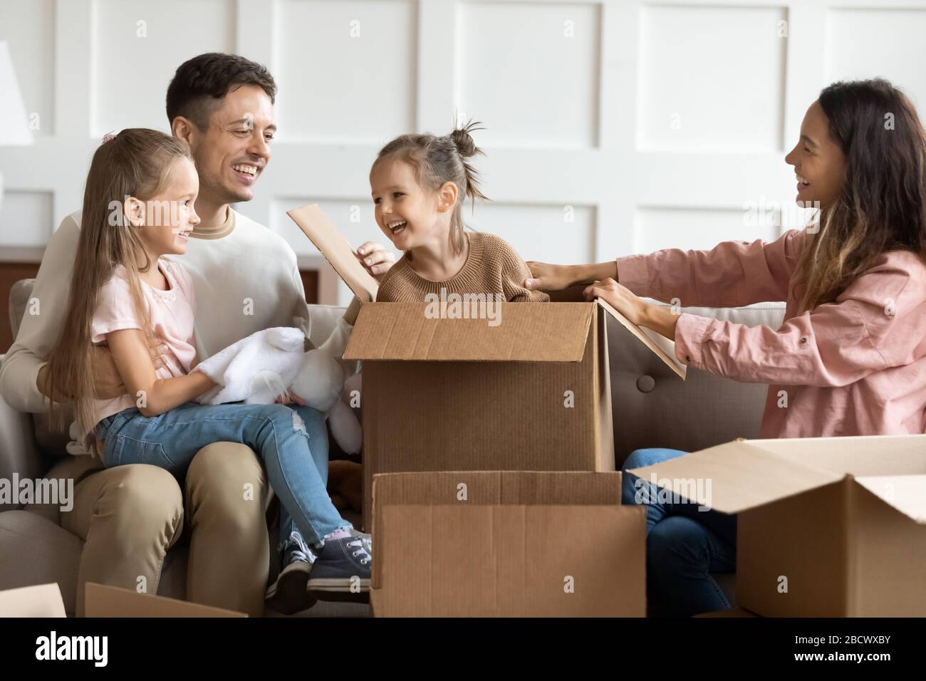 Joyful family couple having fun with children in new apartment. Stock Photo