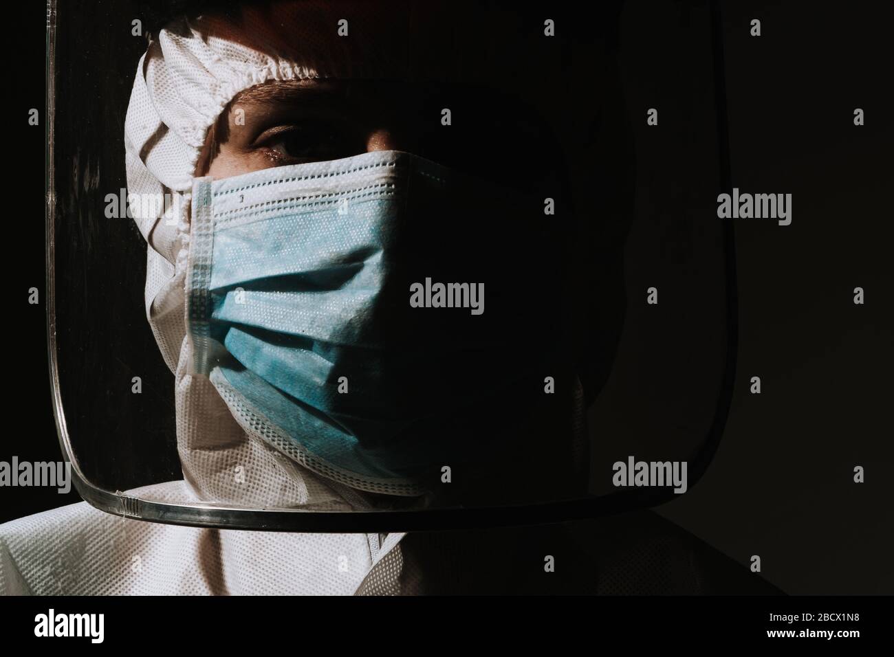 Female doctor sad and serious with face shield and mask for protection of coronavirus covid-19 on black background Stock Photo