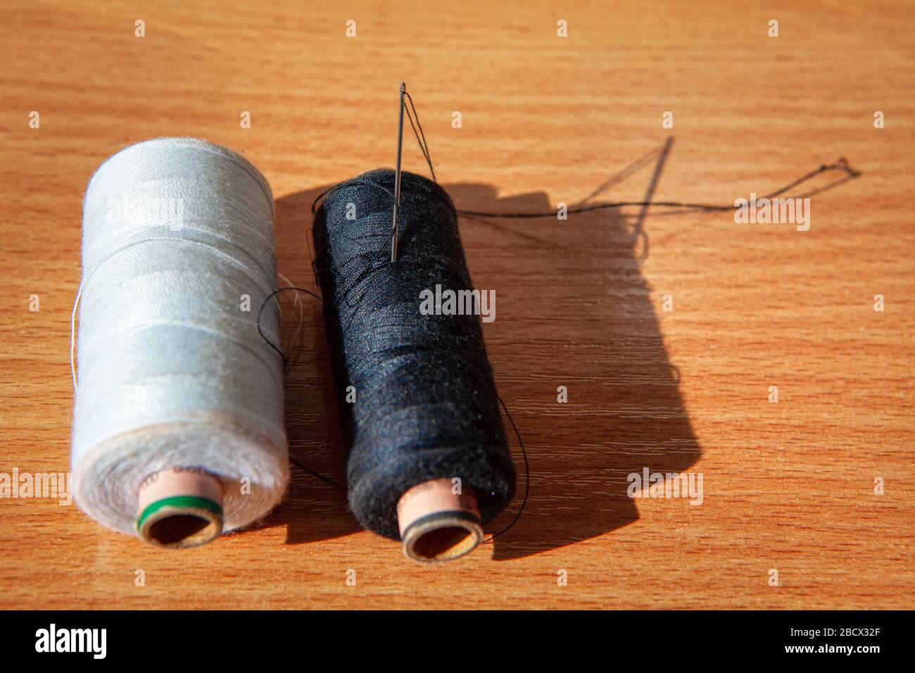 Needle and Bobbin with Black Thread on Black Background Stock