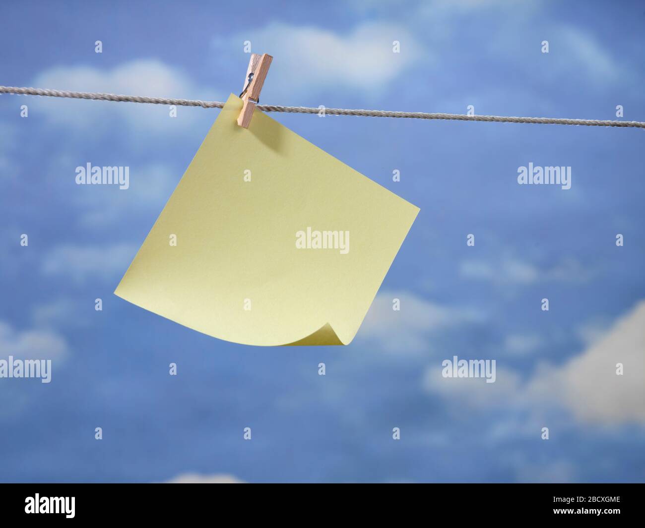 Note paper hanging on clothesline with pretty blue sky Stock Photo