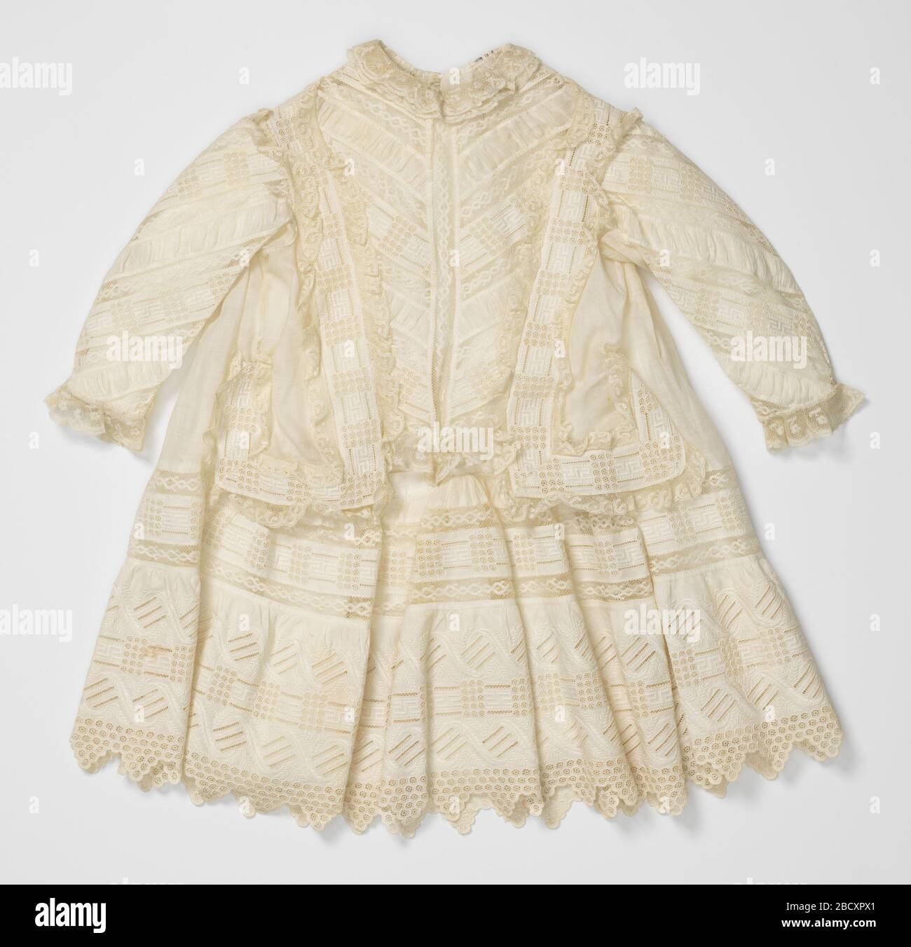 Childs dress. Research in ProgressChild's dress of white cotton. Front of bodice, sleeves and skirt of alternate bands of eyelet embroidery, gathered muslin, and handmade Valenciennes lace. Deep flounce of eyelet embroidery at bottom of skirt. Childs dress Stock Photo