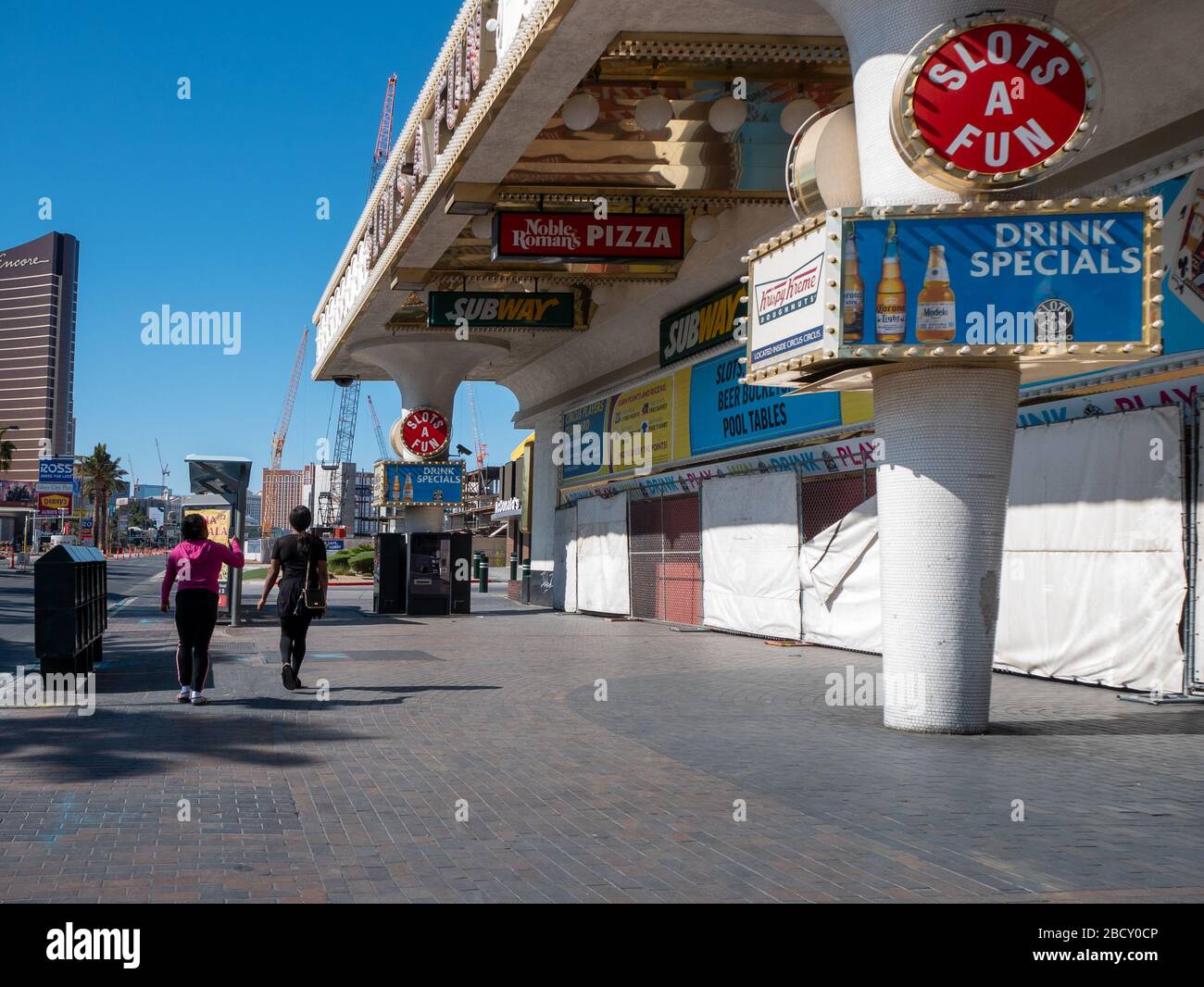 4 April 2020, Las Vegas, Nevada, USA, Two women walking on deserted Las Vegas Boulevard in front of boarded up shops due to Covid-19 shut down Stock Photo