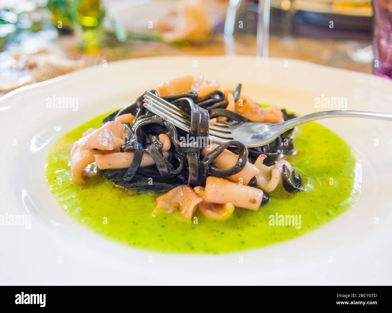 squid ink spaghetti with octopus and squid sauce on a bed of spinach ...