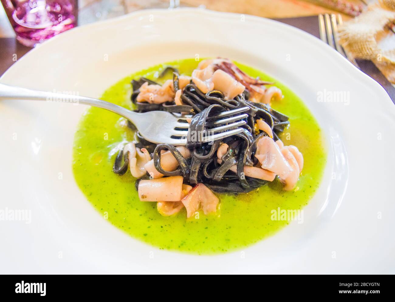 squid ink spaghetti with octopus and squid sauce on a bed of spinach ...