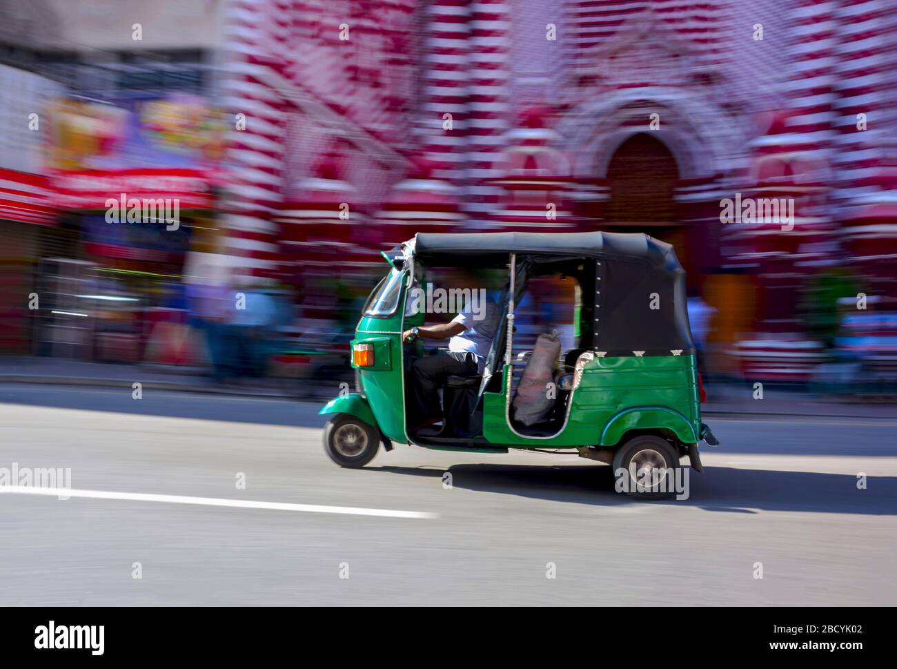 Abstracted Panning Photography Of A Three Wheeler In Front Of Red Mosque In Colombo, Sri Lanka Stock Photo