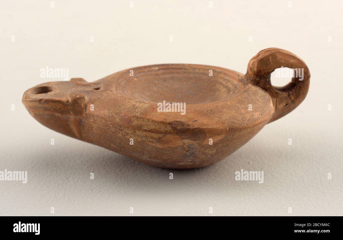 Oil lamp. Research in ProgressHandled lamp with depressed center, spade-shaped spout joined to body with pair of volutes. Marks on base: an impressed foot and a strigil in relief. Oil lamp Stock Photo