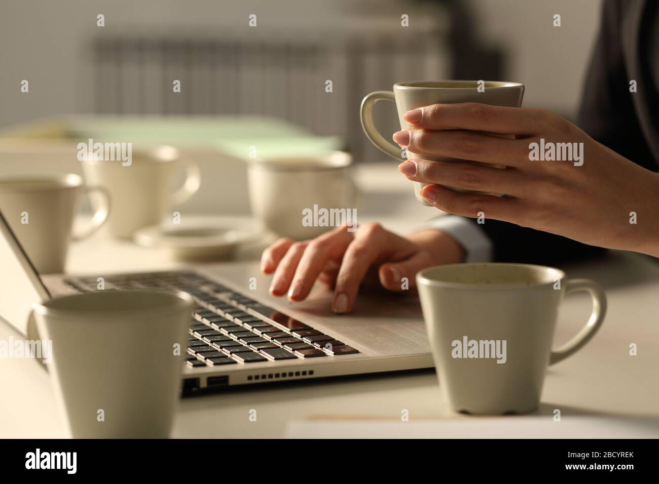 Close up of overworked executive woman hands working late hours wih multiple coffee cups in the office at night Stock Photo