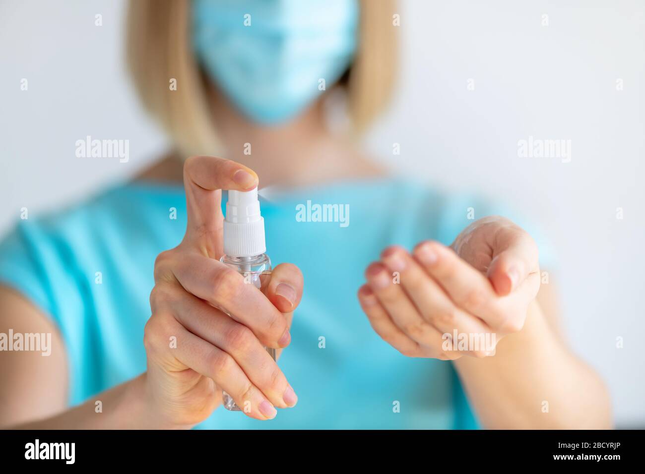Female doctor or nurse in uniform puts a disinfectant spray on her hands. Disinfection and hand washing. Protection against virus and bacteria Stock Photo